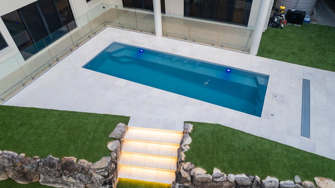 Wide paved pool surround with a custom drop edge and stairway