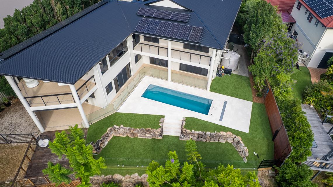 Aerial view of a fibreglass pool set into a landscaped surround with paving, lawn and a retaining wall