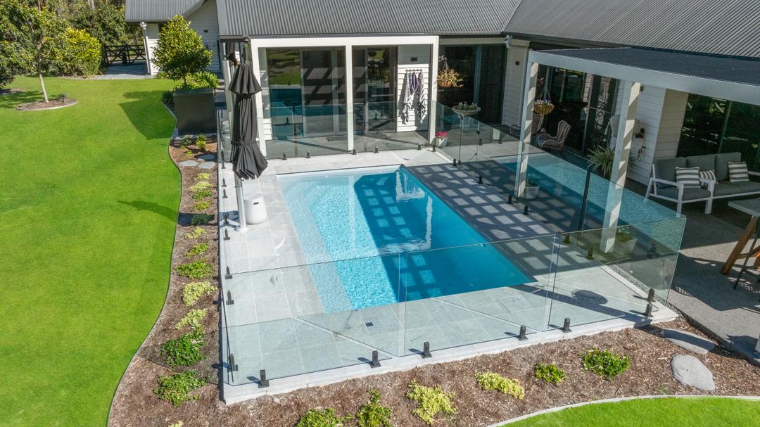 Frameless glass pool fence around a fibreglass pool