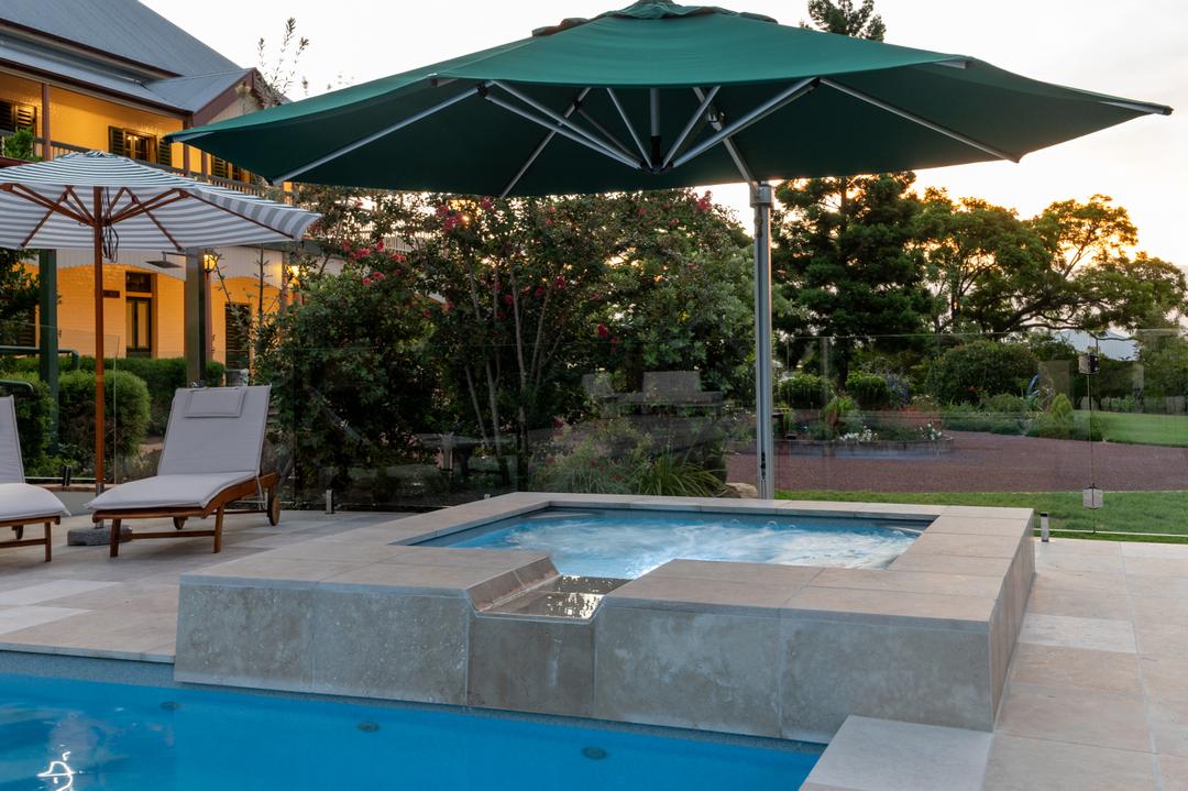 Fibreglass family pool with an attached spillover spa at dusk