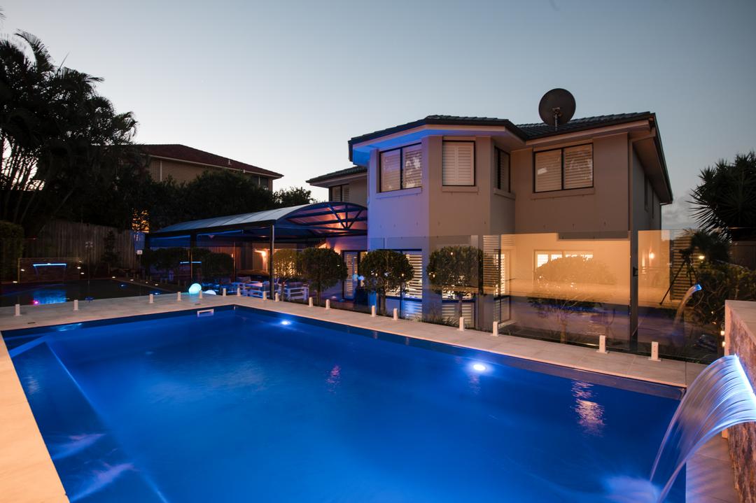 Deck jets arcing water into a fibreglass pool at dusk